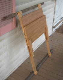 Standing desk with shelves folded up and leaning against wall of house.
 It folds up to about 5 inches thick and the bottom edge is about 1.5 feet
 from the wall.